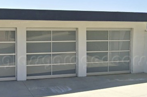 Three modern full-view glass garage doors, offering a contemporary and private façade to a residential garage.