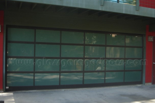 Modern residential garage with a wide full-view obscured bp glass garage door and dark brown framing