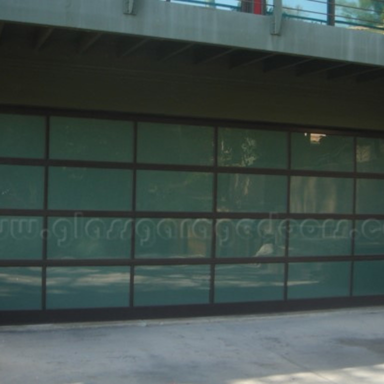 Modern residential garage with a wide full-view obscured bp glass garage door and dark brown framing