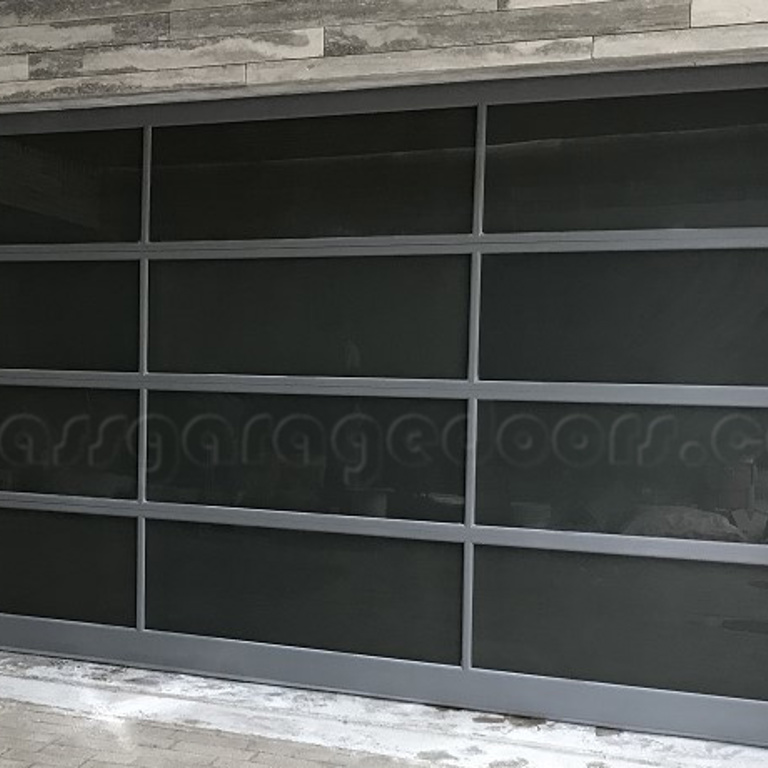 modern bp glass garage door with dark glass panels and sleek gray aluminum frames, providing privacy and a sophisticated look for a contemporary home or commercial building with stone cladding.